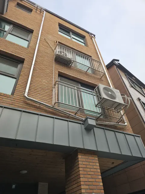 황갈색 벽돌 4층 건물 우수관교체 후 외벽
