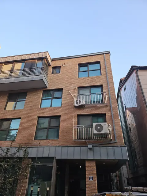 황갈색 벽돌 4층 건물 우수관교체 전 외벽