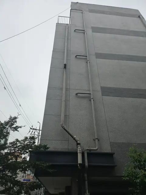 회색 외벽 5층 건물 우수관교체 전 측면 배관